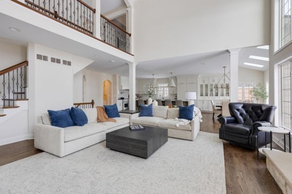 Simple and contemporary living room with white couch, blue throw pillows, and a high ceiling with an overlooking banister