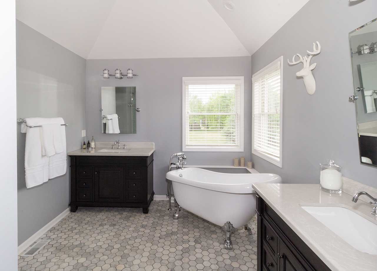 Luxurious master bathroom with a stand alone claw footed tub between two vanities