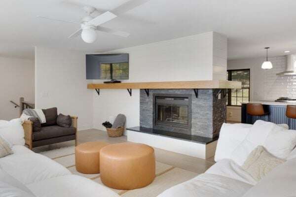 Living room with a classic fireplace. Leather ottoman in the living room surrounded by white sofas - Holidays On Heather 16