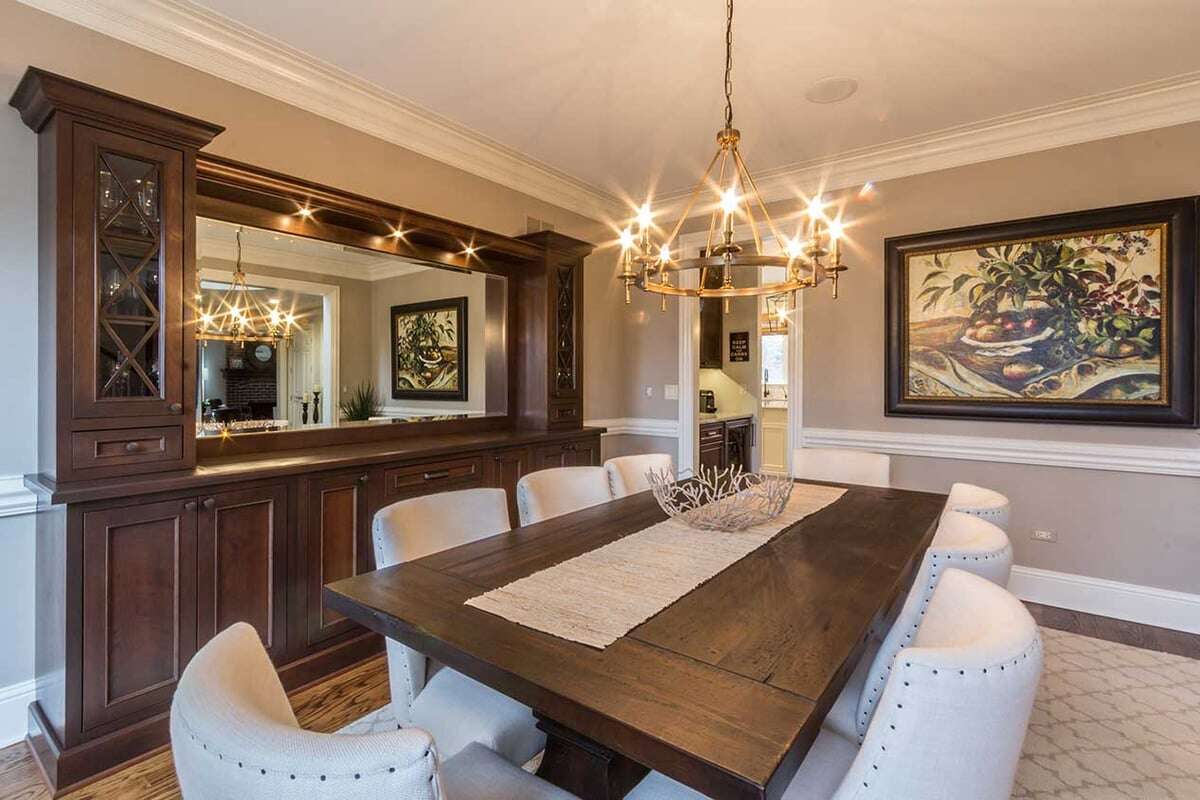 A wooden dinning table with leather dinning seats and a classic chandelier hanging from the ceiling Saddleridge House 10