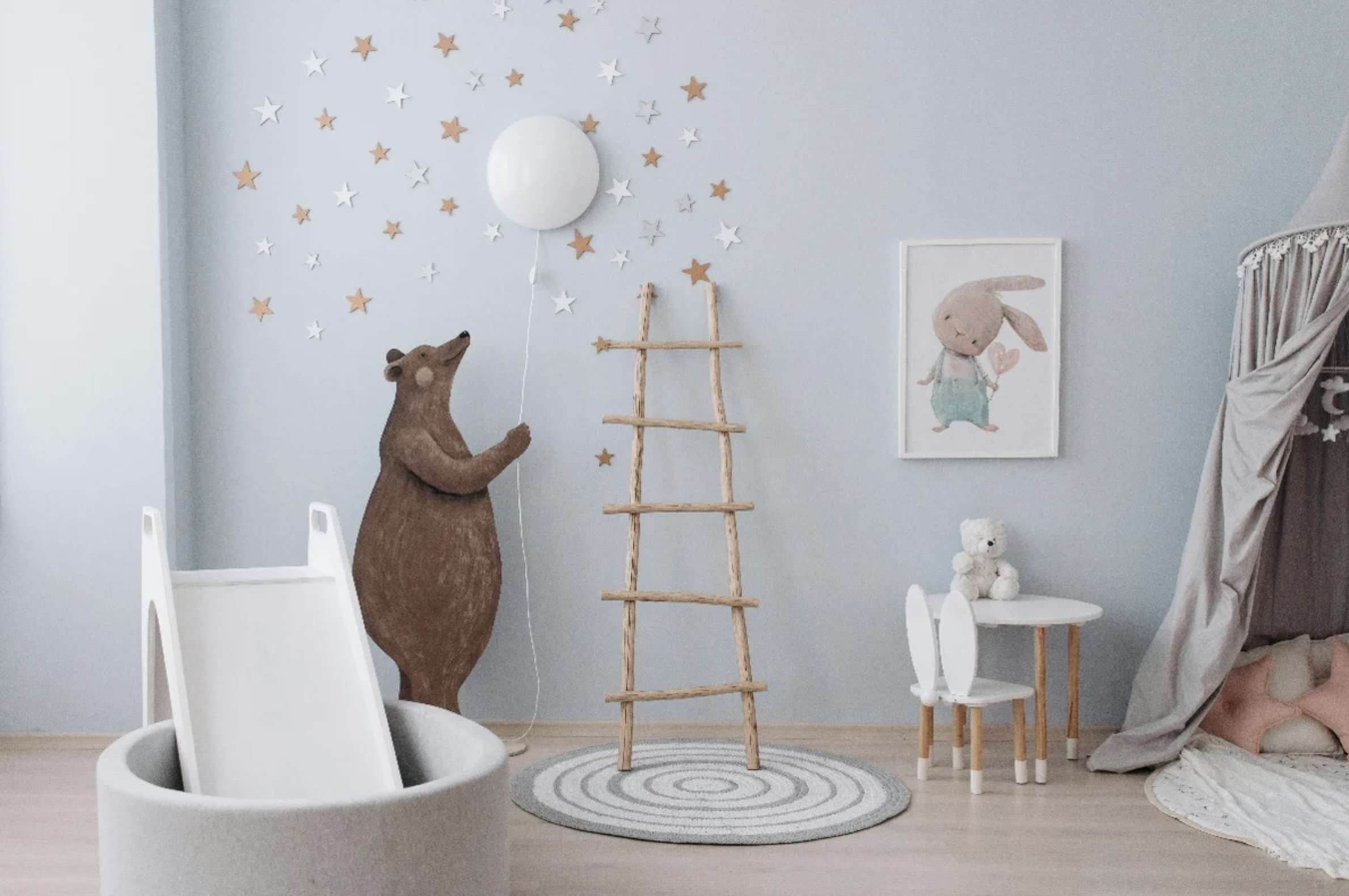 A multifunctional childrens nursery with grey walls, a small blanket ladder, and a brown cuddly bear