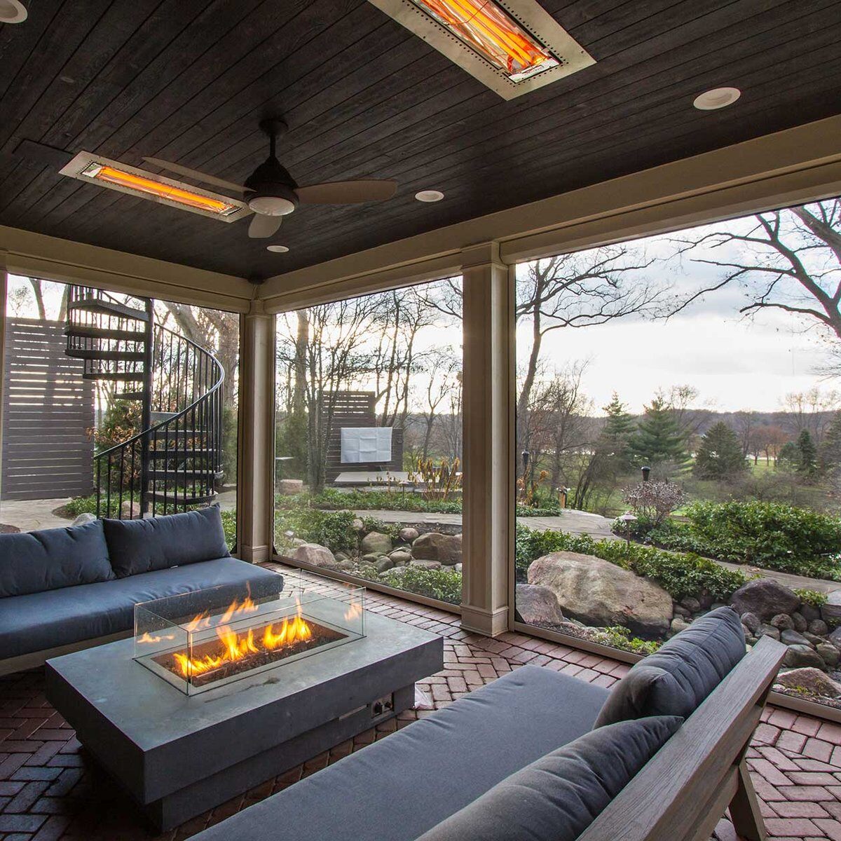 Outdoor screened-in porch with a fireplace built into the table for seating