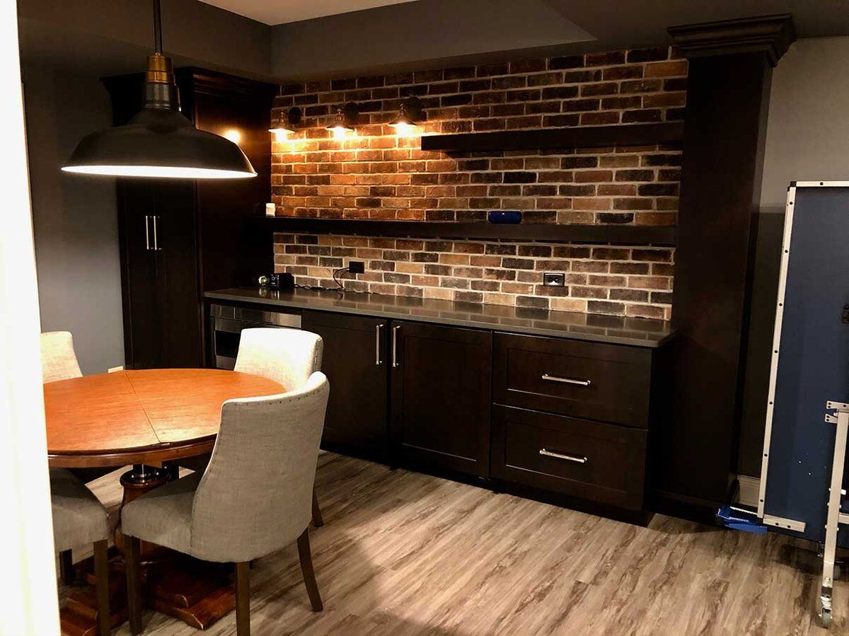 Basement seating area with a small shelf with a hutch against a brick wall with a seating area for four in front