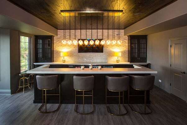 Well lit basement bar with lots of pendant light hung above 4 stools