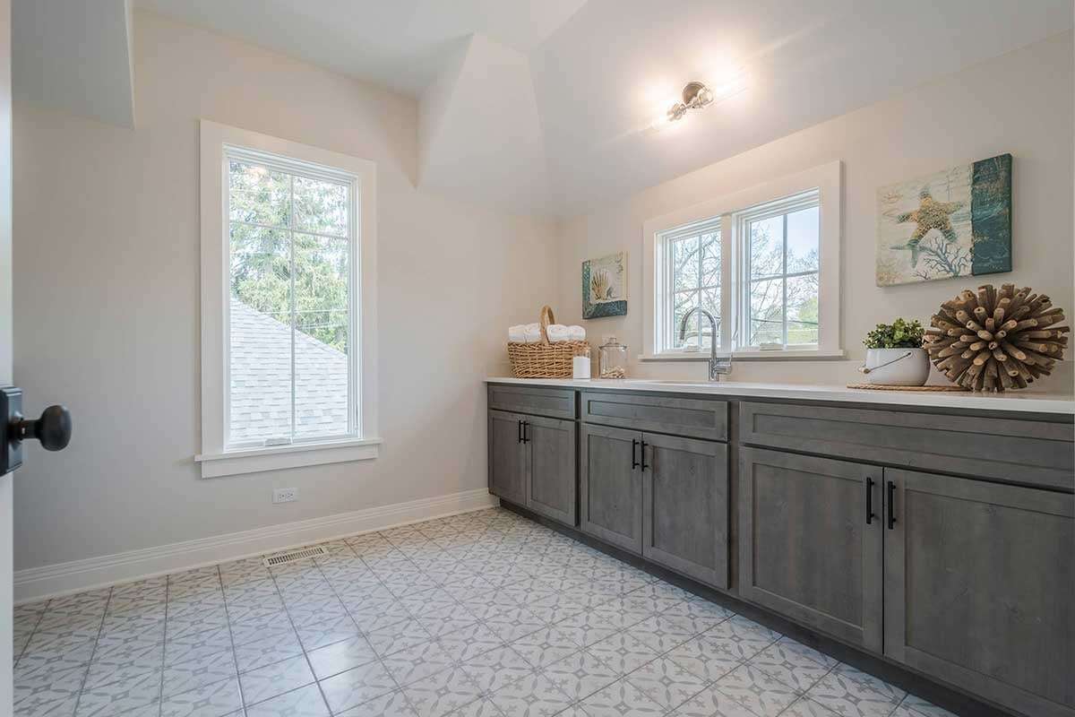 High end bathroom with gray cabinetry, lots of natural light, and lots of wall decor that is of coastal design