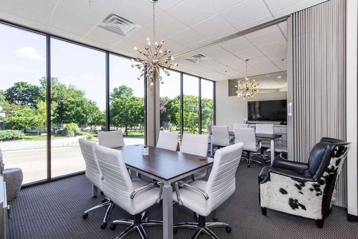 Luxurious meeting room with two matching desks that each have 6 white rolling chairs