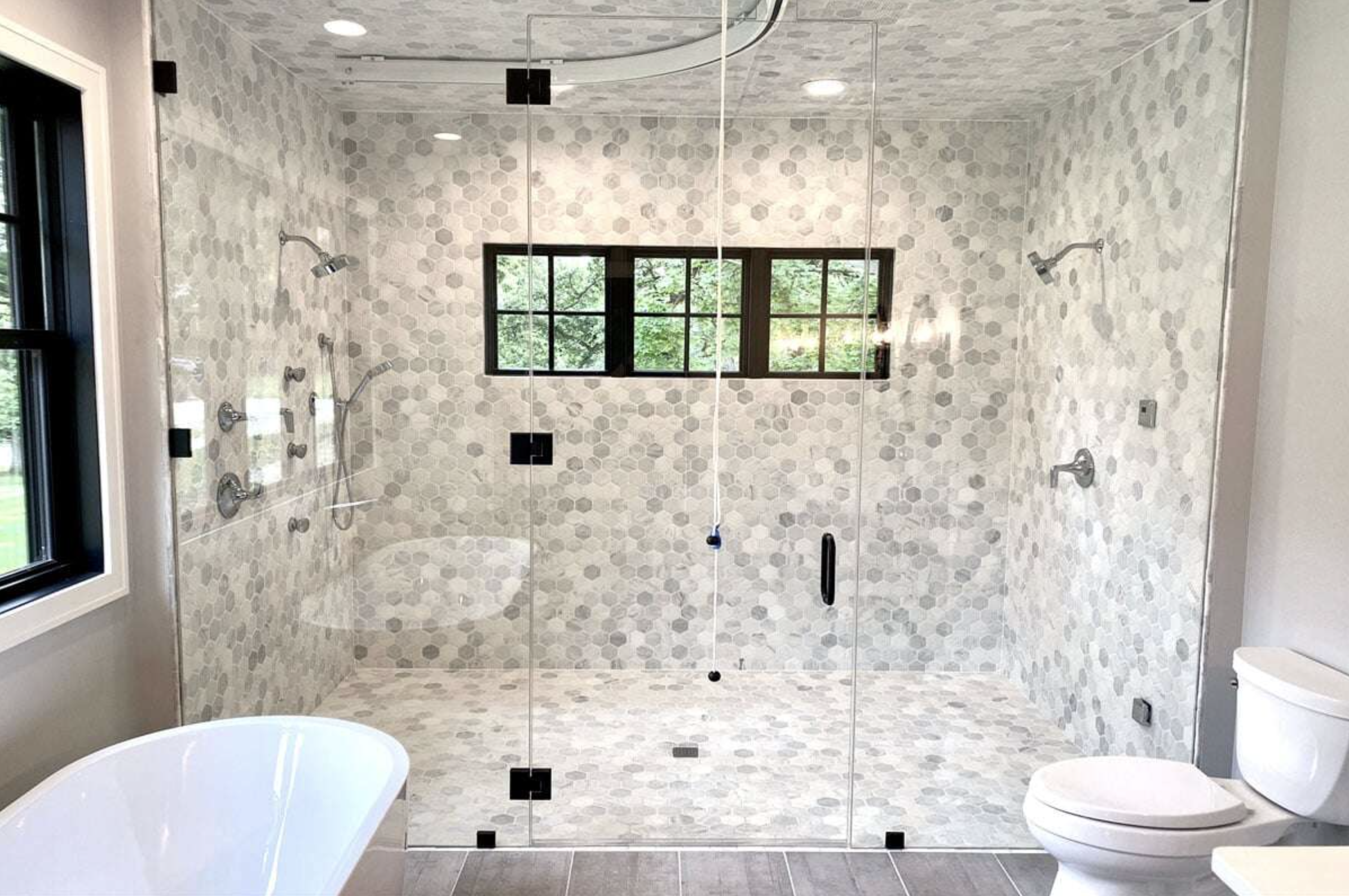 Elegant and luxurious hexagonal bathroom tile work in a double headed walk-in shower. Also features many high-tech ammenities