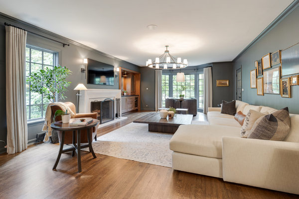 Elegant and traditional living room with hardwood floors, a chandelier, and a white sofa with a chaise attached