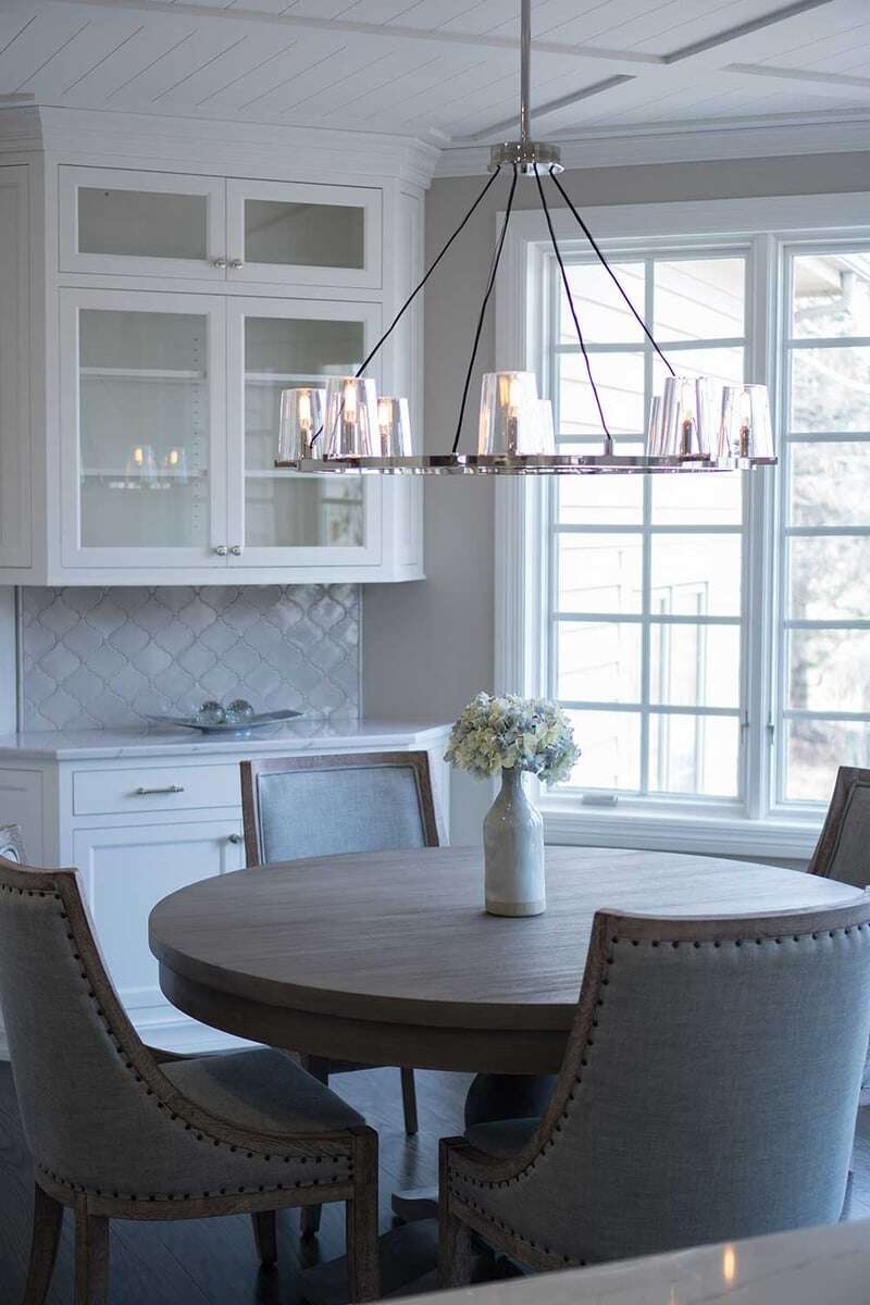 Dining room circular table with a flower vase on top and surrounded by 4 fabric chairs