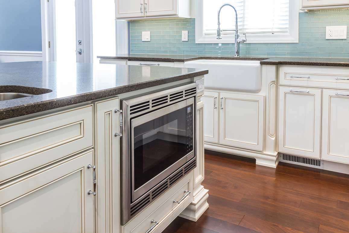 stainless steel microwave built into a white kitchen island