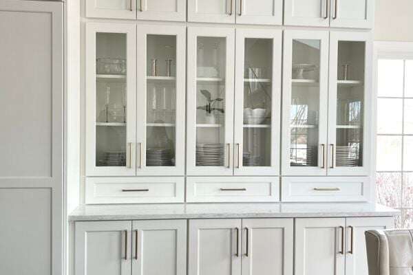 Kitchen cabinets with white finish and glass pane doors showing the china inside