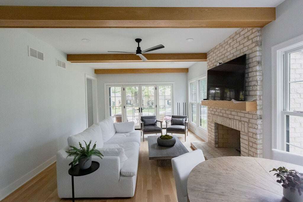 cozy living room with exposed rafters, hardwood floors, and double doors to the patio in the background