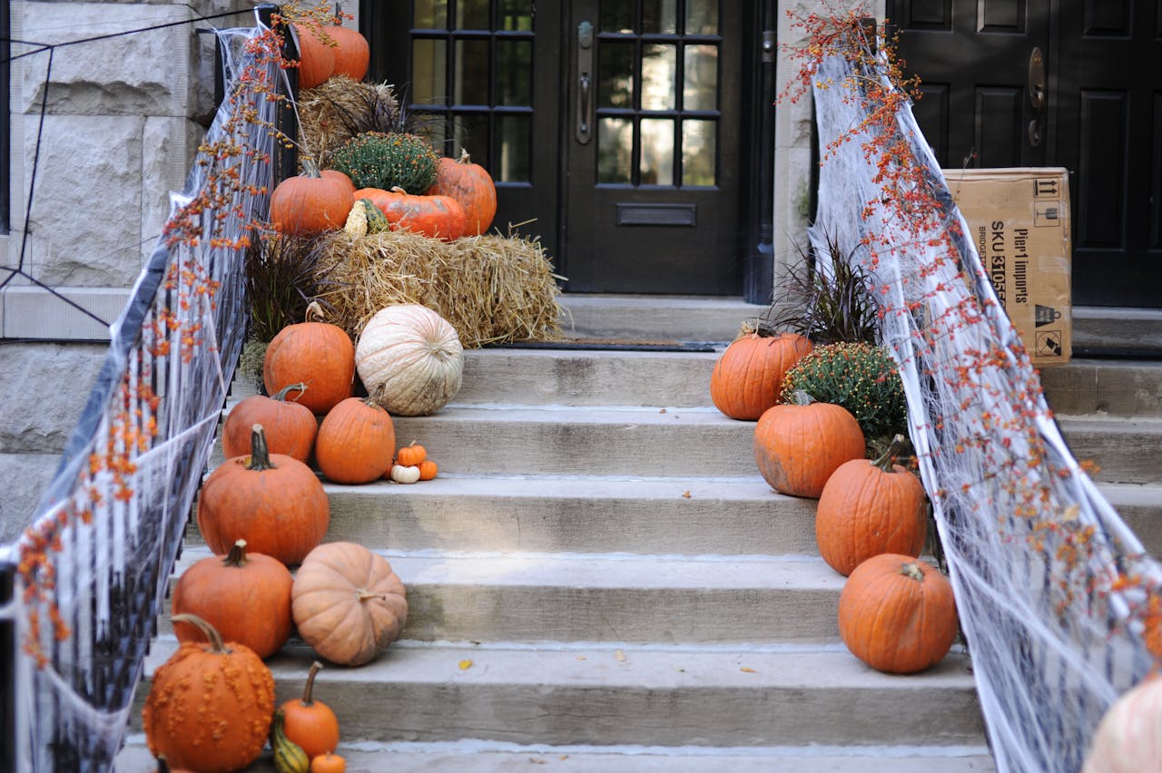 Home entryway with staircase decorated for Halloween with pumpkins, spiderwebs, and fall banister garland